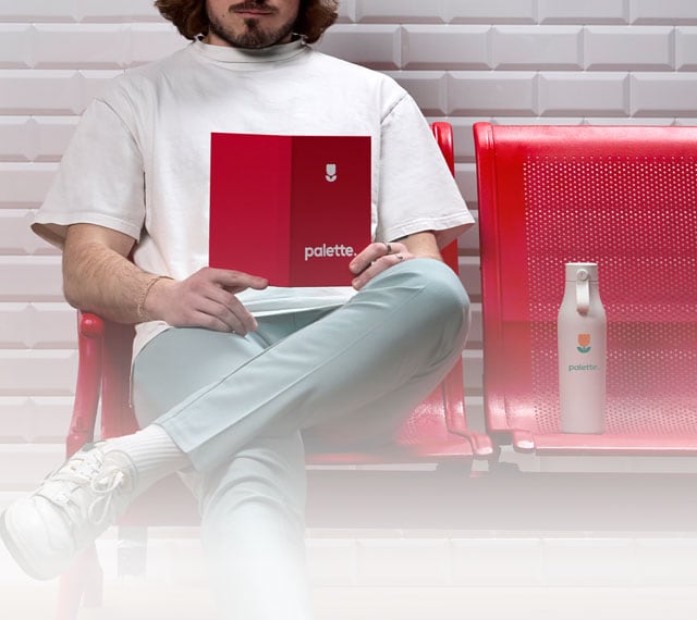 Hombre con un cuaderno personalizado y sentado en un banco con una botella de agua personalizada.