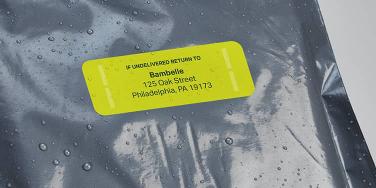 Green waterproof address sticker on a wet plastic mailer bag