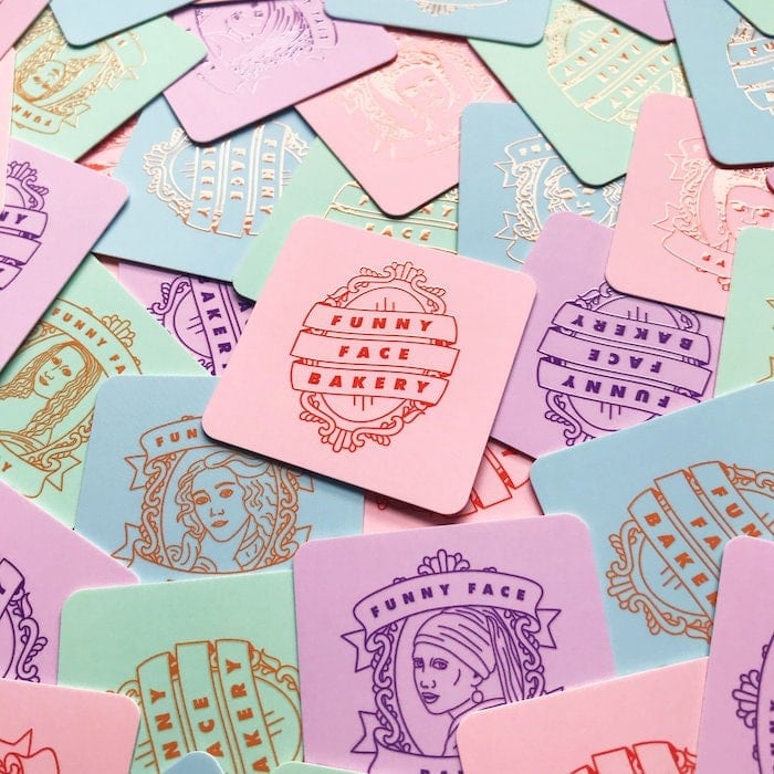 Funny Face Bakery square business cards in various colors and designs including blue Botticelli cards, green Mona Lisa cards, pink Frida Kahlo cards and purple Girl with a pearl earring card as well as mirror illustrations by Lucy Jenn