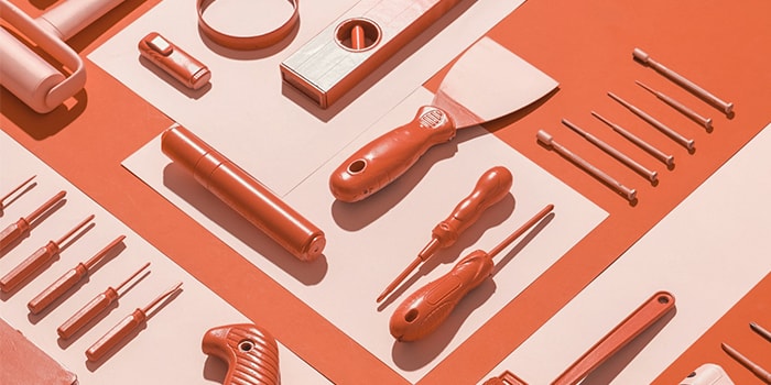 Orange tools including screwdrivers and paint roll on an orange background