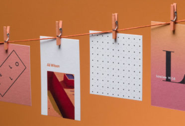 4 business cards in various designs hanging from a laundry line