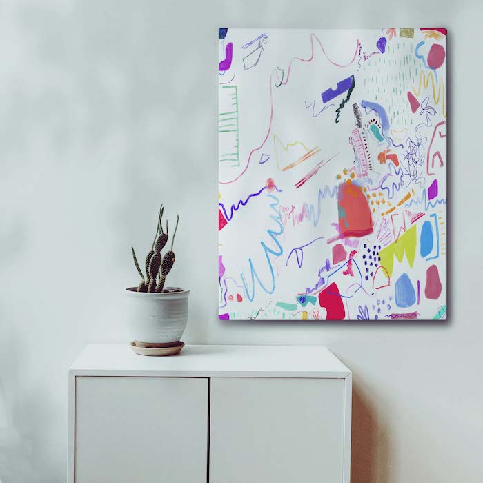 Abstract colorful painting by Christen Robinson next to a plant