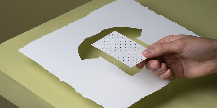 Sheet of cotton paper with tshirt shape cut out and cotton business card in the middle