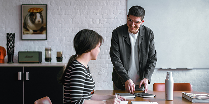 Seated woman and standing man chatting in the workplace