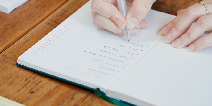 Person writing a to-do list in a notebook