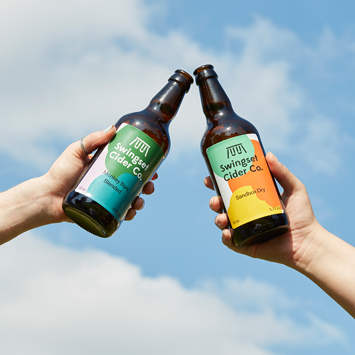 Beers being clinked together to celebrate an outdoor event 