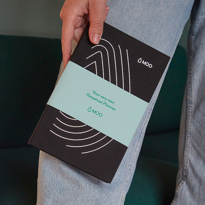 Person holding a branded Perpetual Planner featuring a customized Belly Band.