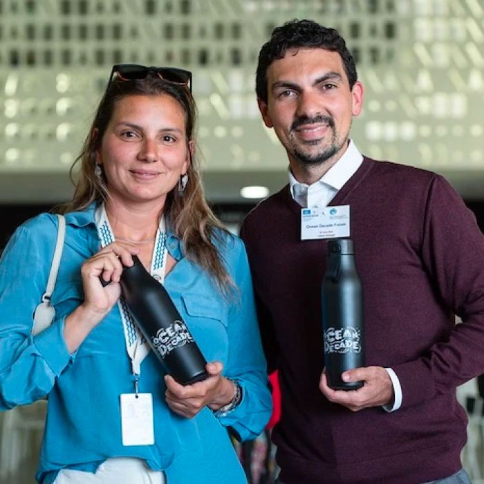 Two people holding branded Water Bottles for Unicef Ocean Decade partnership.
