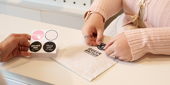 Evie packaging customer order at Queer Britain.