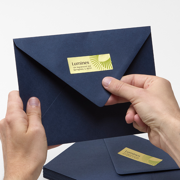 Person adding metallic sticker to envelope.