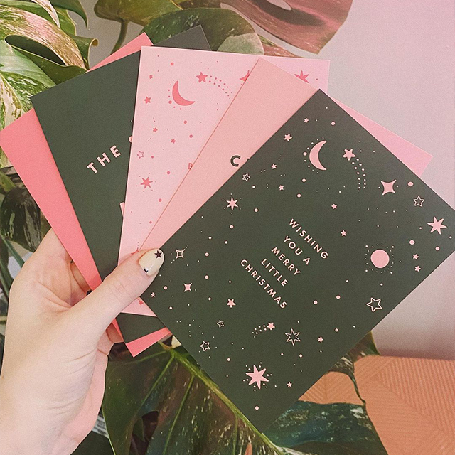 Una selección de tarjetas de felicitación negras y rosas con mensajes festivos