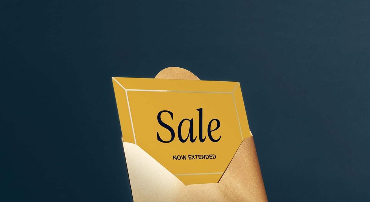 A postcard in an gold envelope saying \'sale now on\'