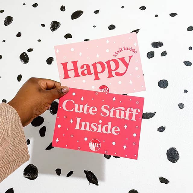 Hand holding one Happy postcard and one Cute Stuff Inside postcard by Hey Bre Creative Studio