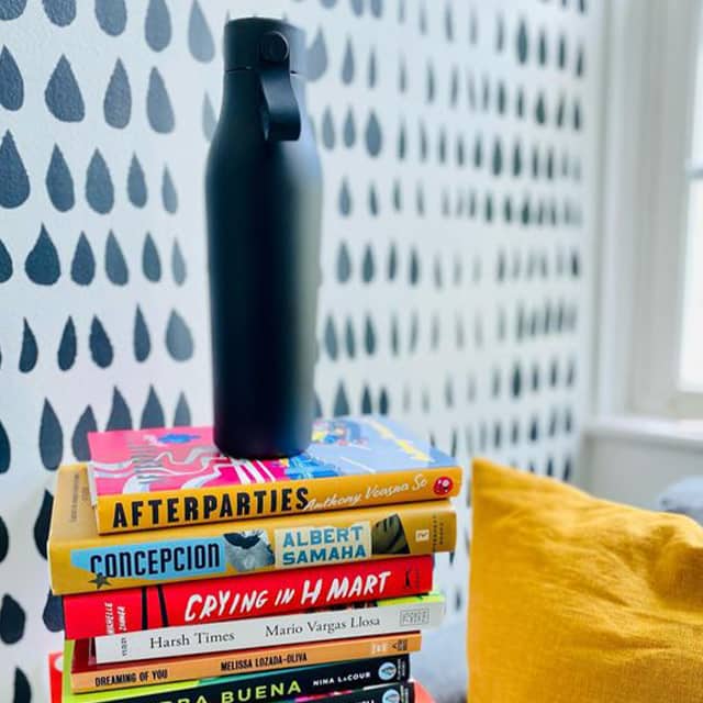 Black drink bottle on top of a pile of books