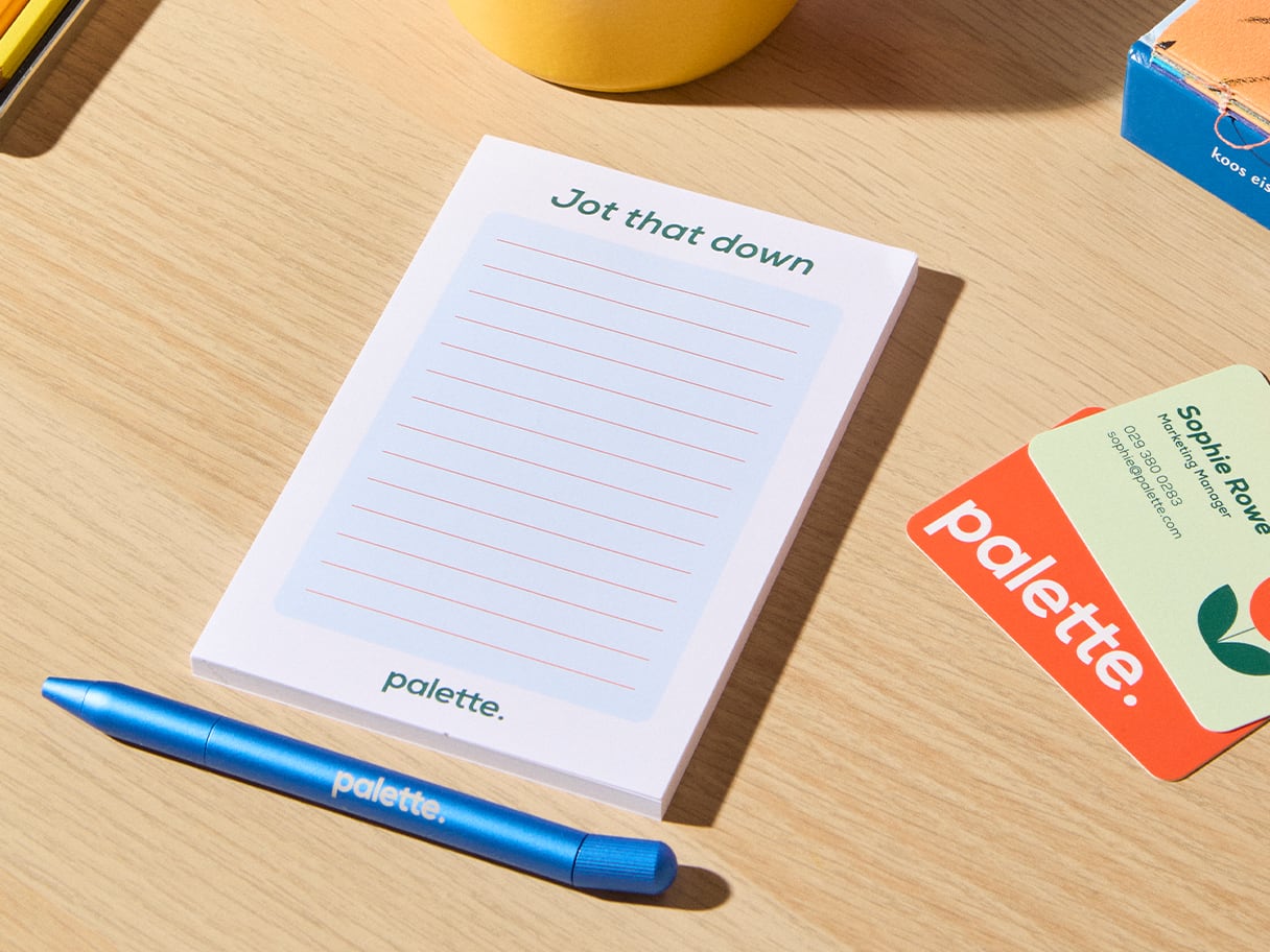 A notepad on a table with a pen and business cards