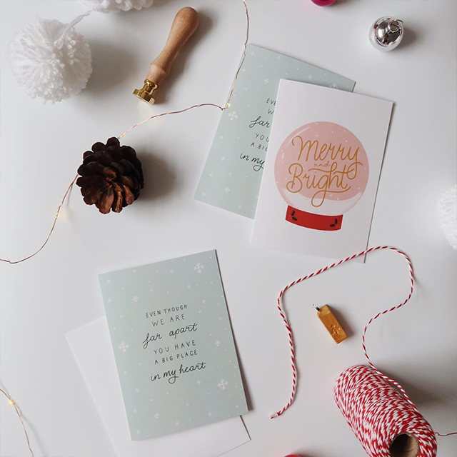 Trois cartes de vœux de saison et une enveloppe entourées de décorations festives.