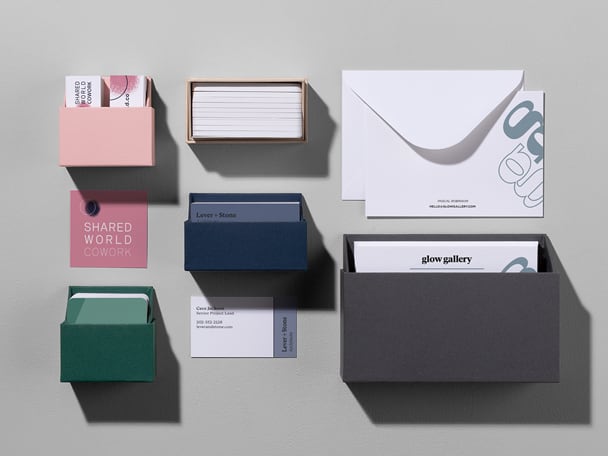 Caja de tarjetas de presentación rosa, verde, azul marino y beige, sobre blanco con tarjeta de notas y caja de tarjetas de notas gris