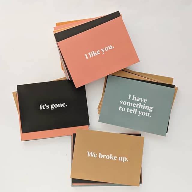 4 piles of MOO Postcards by Moyenne Club with messaging for different occasions, from I like you to We broke up