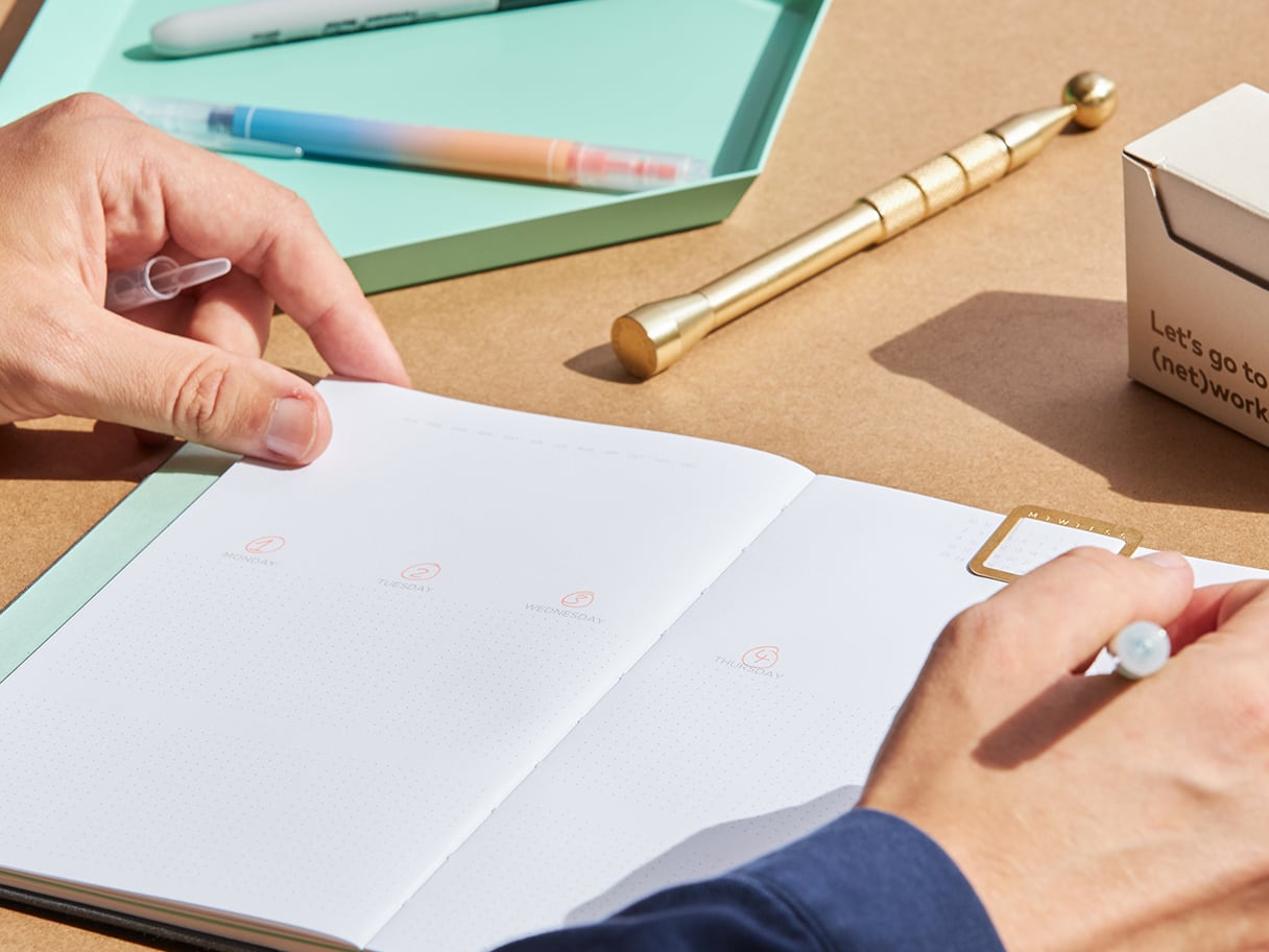 Une personne qui écrit dans un agenda ouvert.