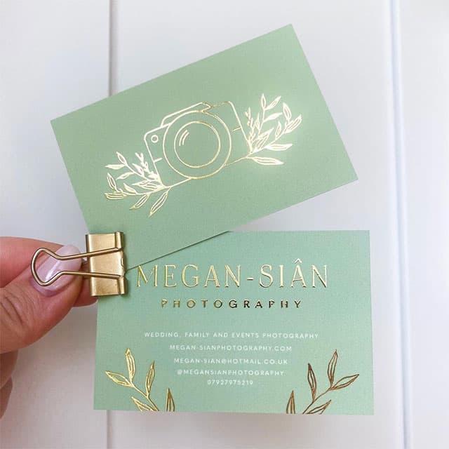 Hand holding two gold foil business cards