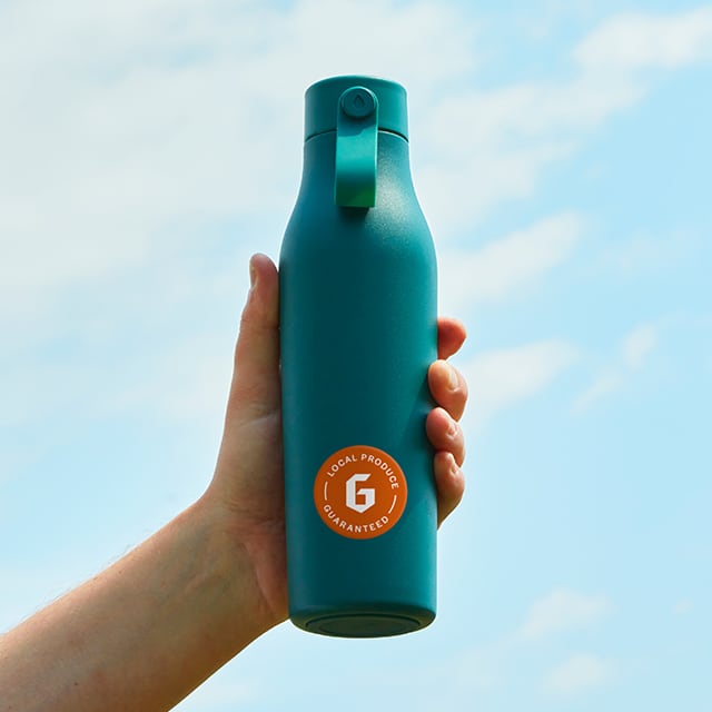 Flatlay photography of five water bottles in white, black, pink, blue, and green. Their lids are off.