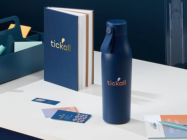 Borraccia blu personalizzata con logo, taccuino blu con copertina rigida, materiale di marketing di marca, penna e un cestino blu da scrivania su un tavolo