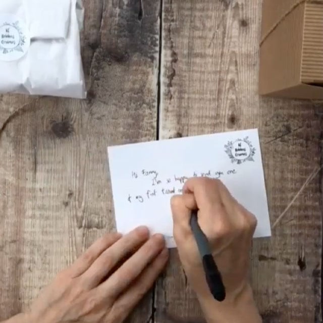 Une main écrivant sur une carte postale