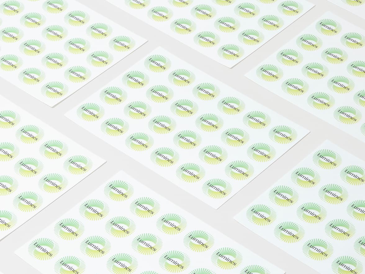 A collection of customized clear round stickers with a light green spiral circle and the word 'Lumines' printed on it.