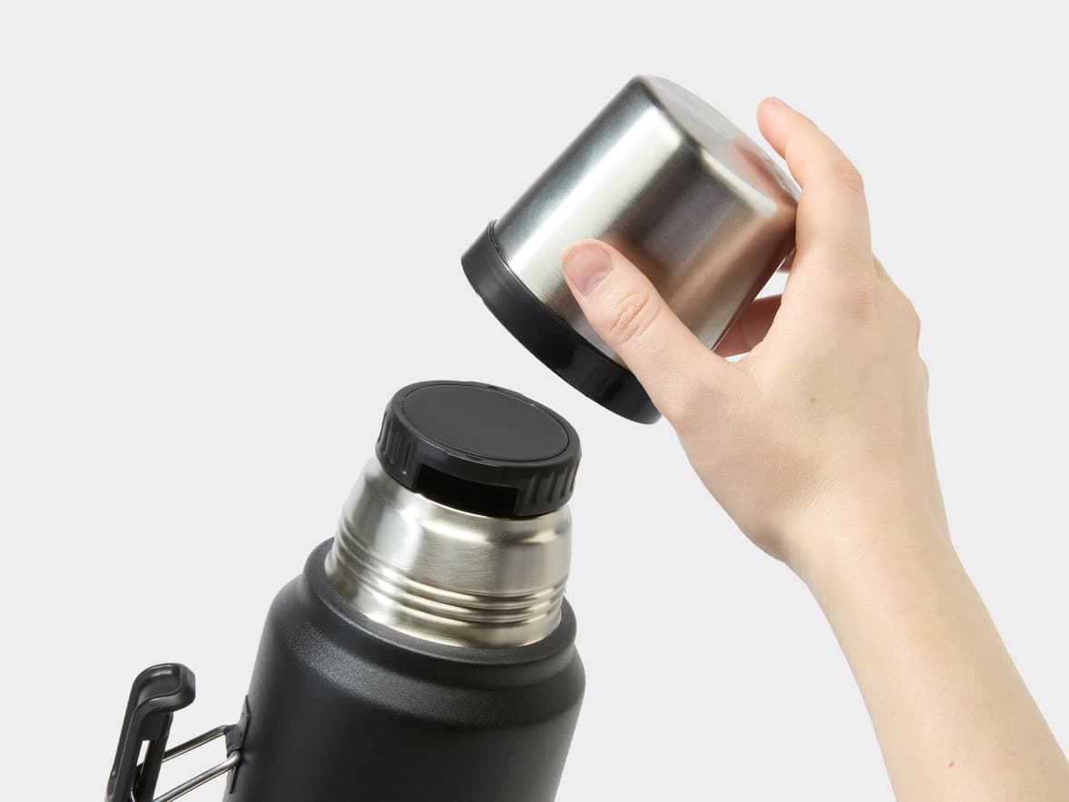 Shot of hands removing the lid of the Stanley Classic Bottle in Black