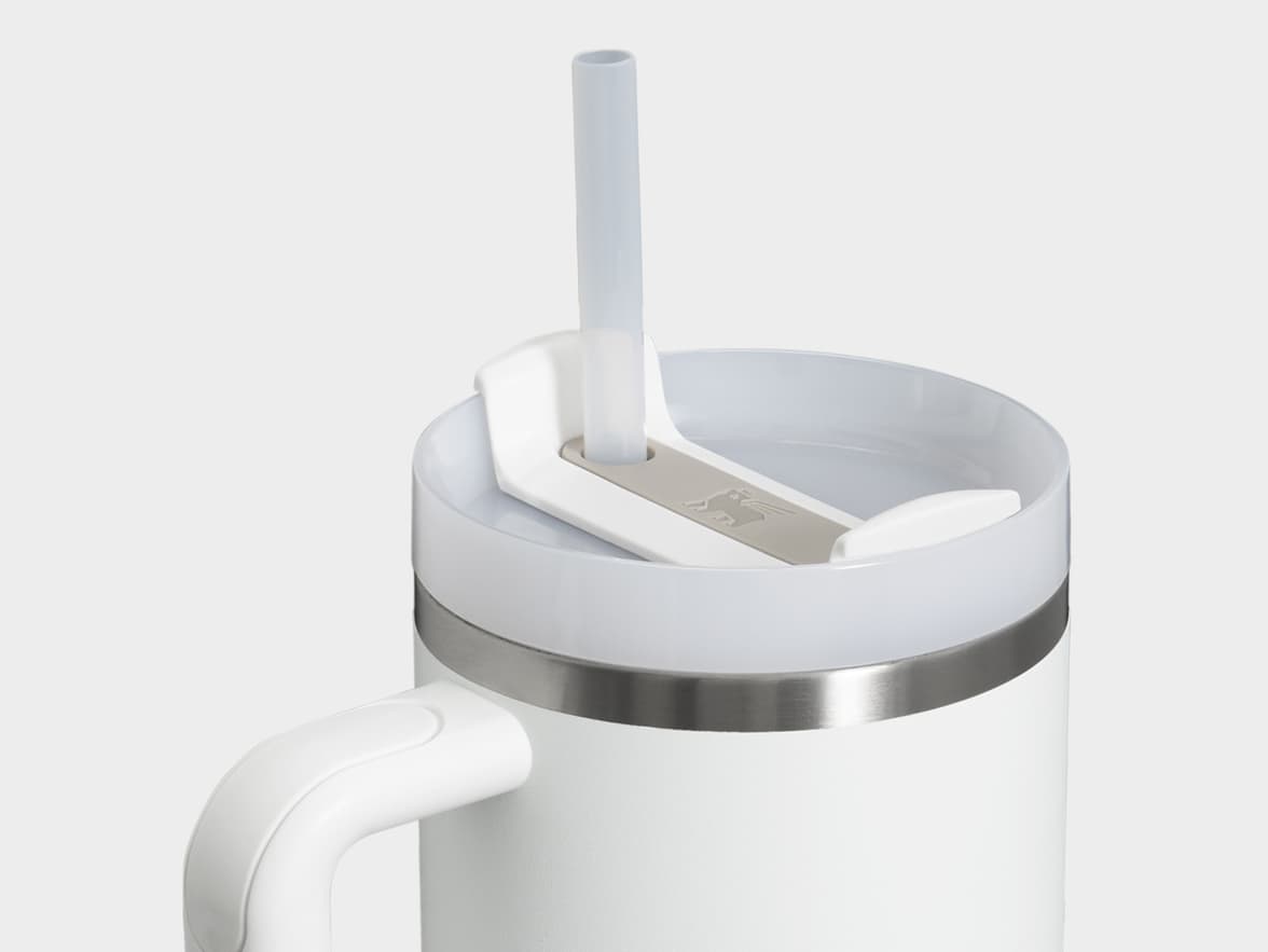 A white travel mug with a handle, a stainless steel band, and a translucent lid with a straw.