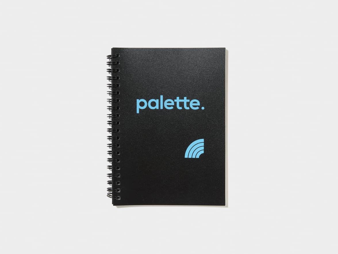Black spiral-bound notebook with the brand "palette." and a partial rainbow logo in blue.