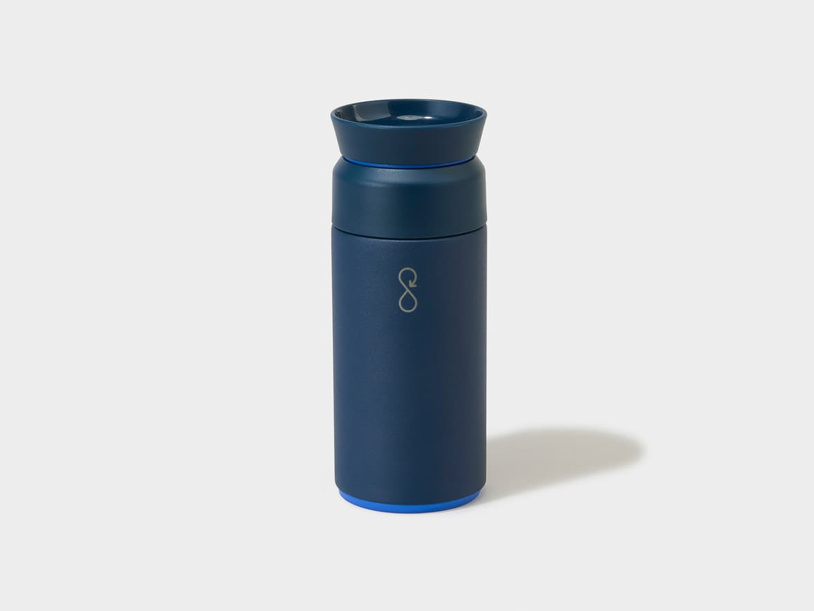 Navy blue travel mug with a silver infinity-like logo on its side and blue accent rings.
