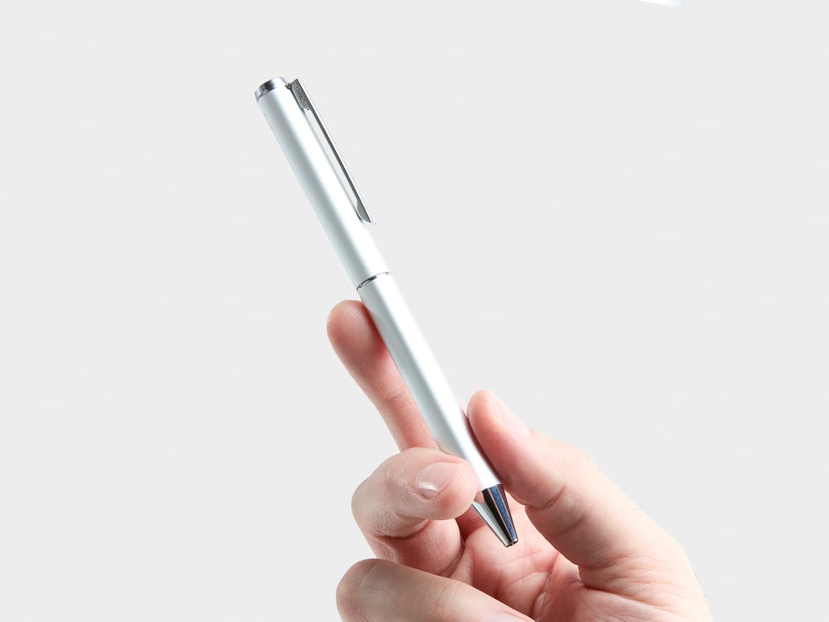 A hand holds a silver ballpoint pen with "CHINA" engraved on its clip.