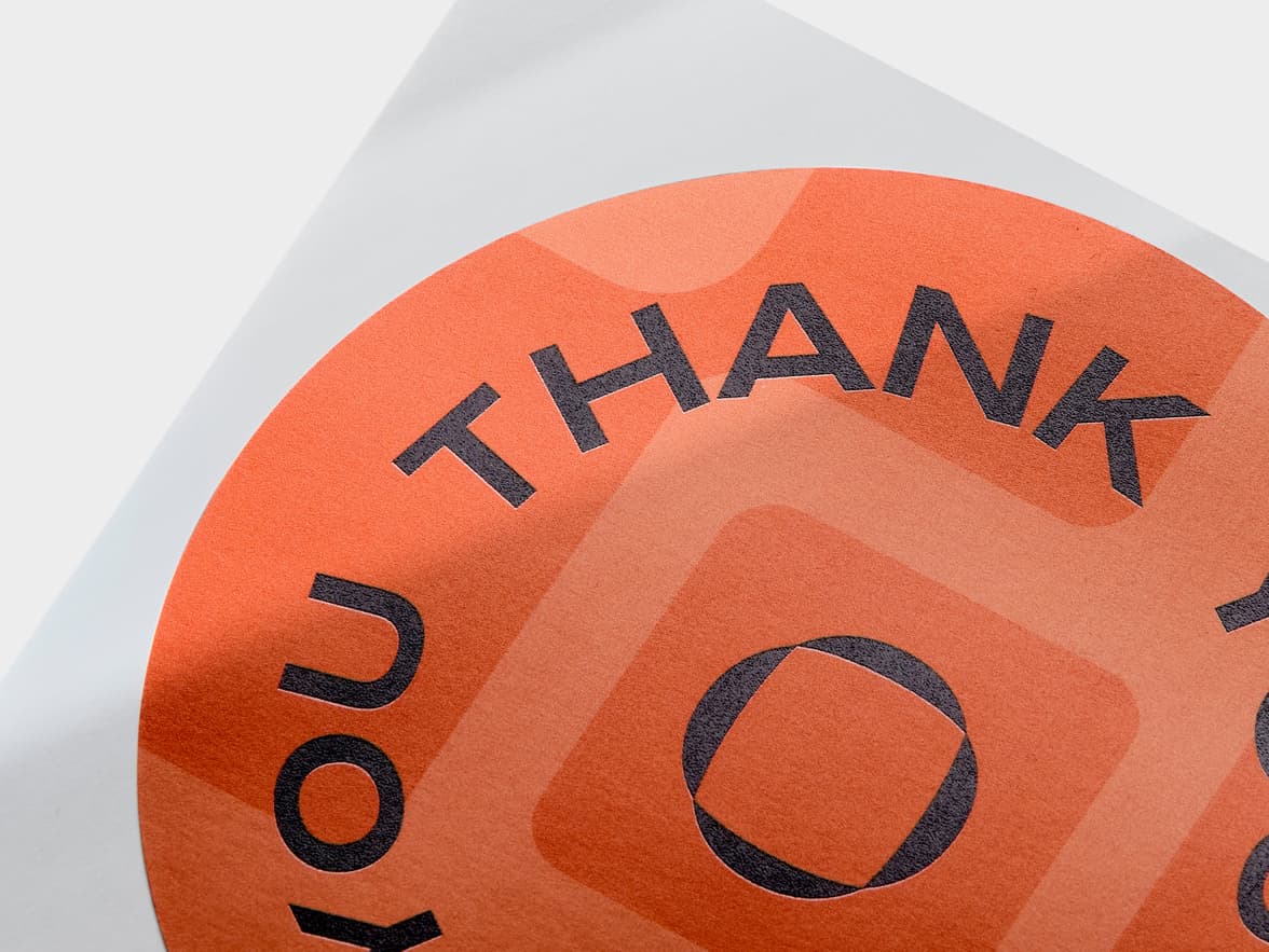 A close up of an orange customized round coated sticker.