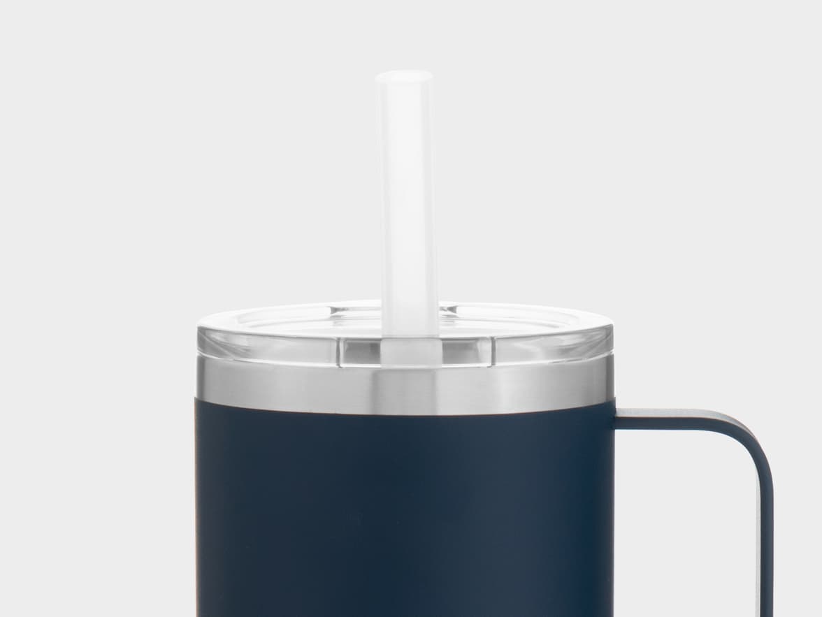 A close-up shot of the top of a dark blue travel mug with a silver band, a clear lid, and a clear straw inserted through the lid. A dark handle is visible on the right side.