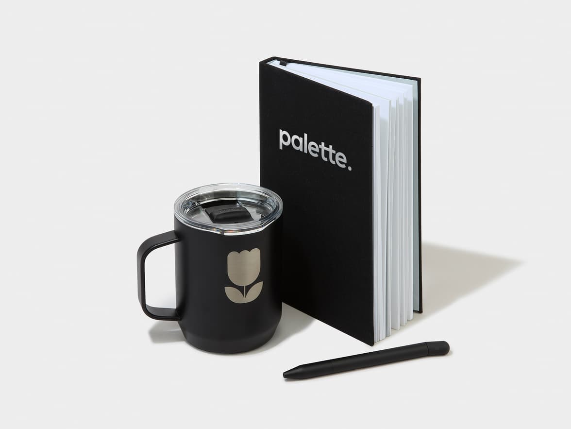 Black "palette." notebook, black travel mug with a tulip logo, and a black pen.