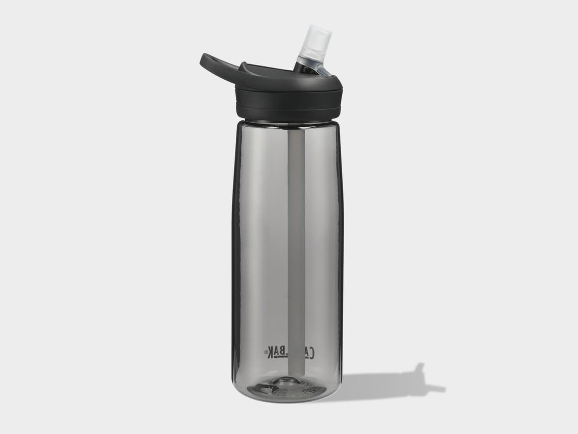 A smoked grey water bottle with a black lid and a clear straw, casting a shadow.