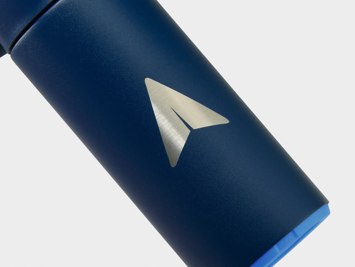 Dark blue water bottle featuring a silver paper plane logo, a bright blue bottom, and a green strap.