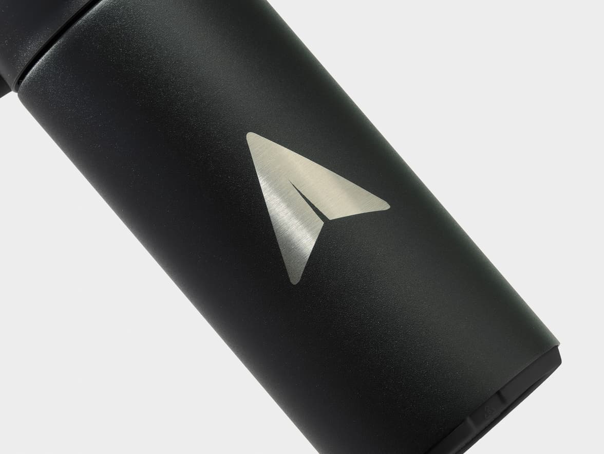 Black textured bottle with a silver paper airplane logo.