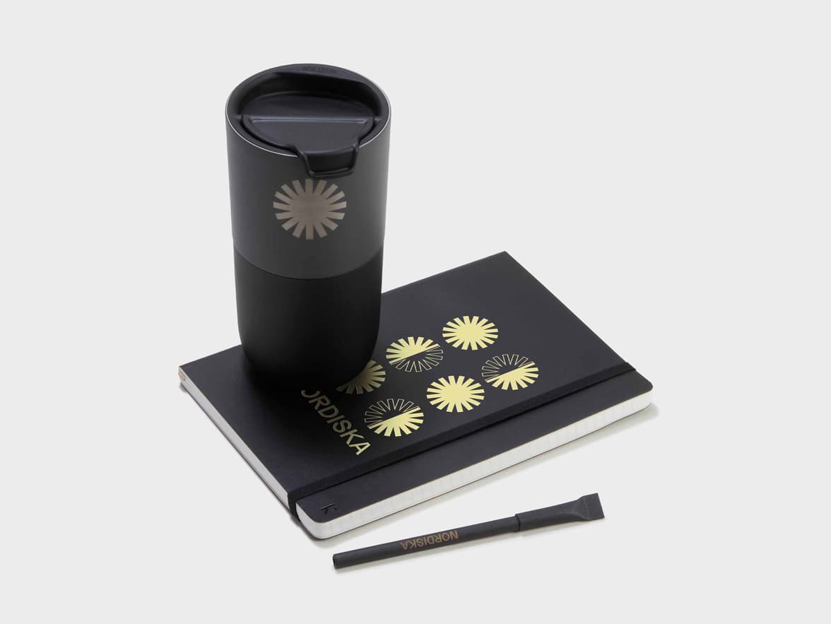 Collection shot of the Black Karst Stone Paper Softcover Notebook with a Tumbler and a Pen
