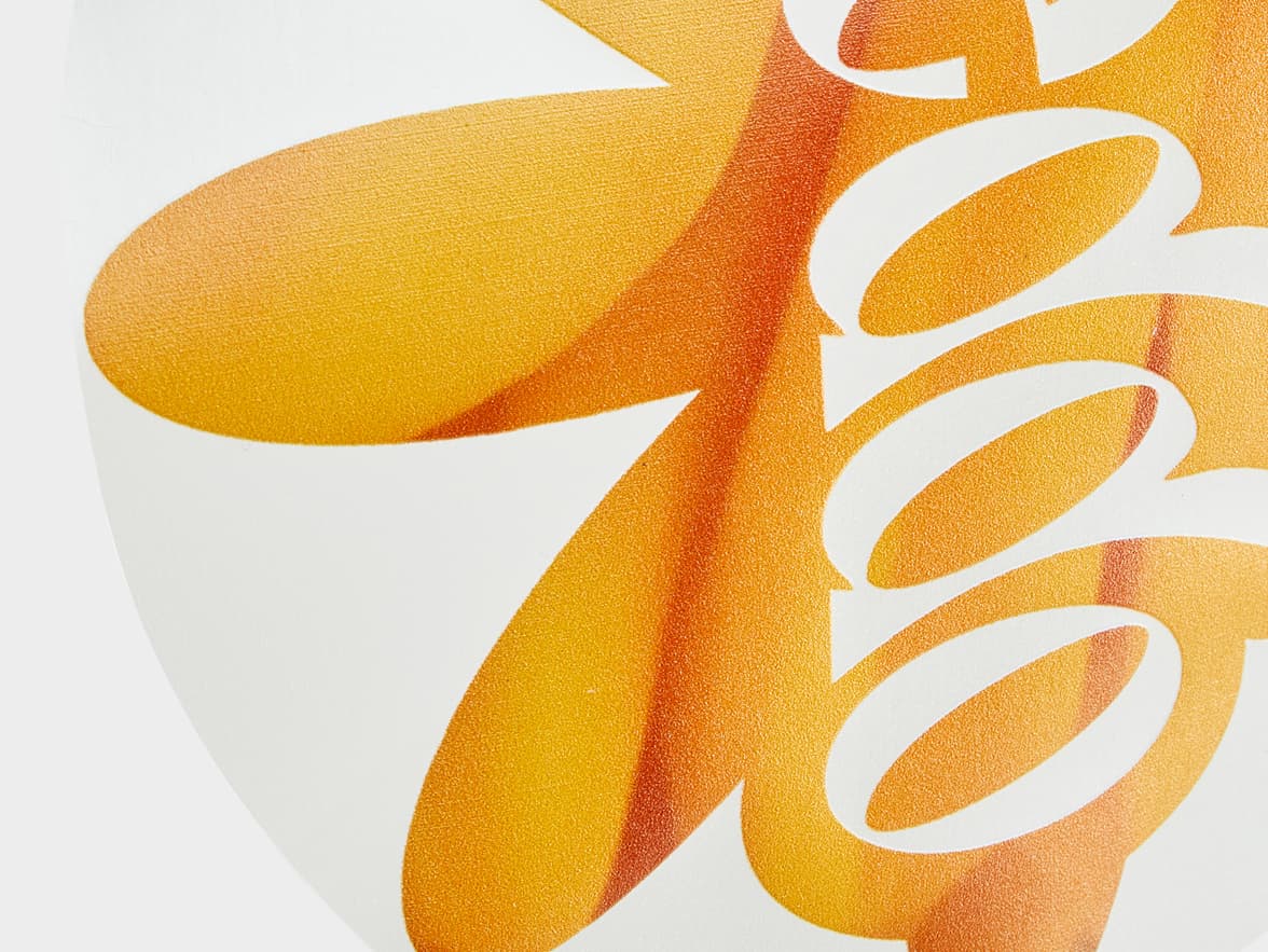 A close up image of a round clear sticker with an orange flower printed on it.