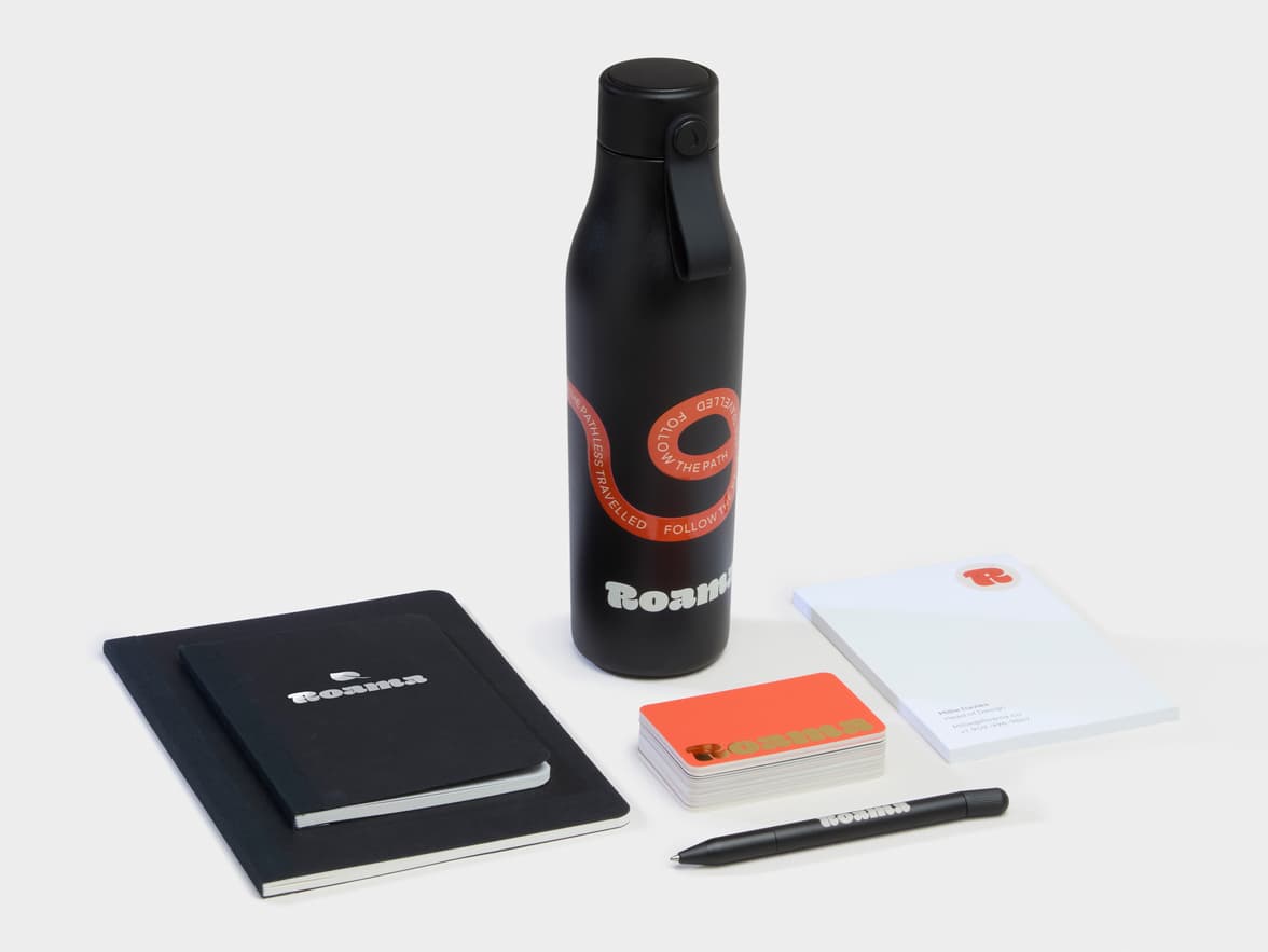 A collection of Branded Merchandise including a black water bottle, black pen and notebooks.