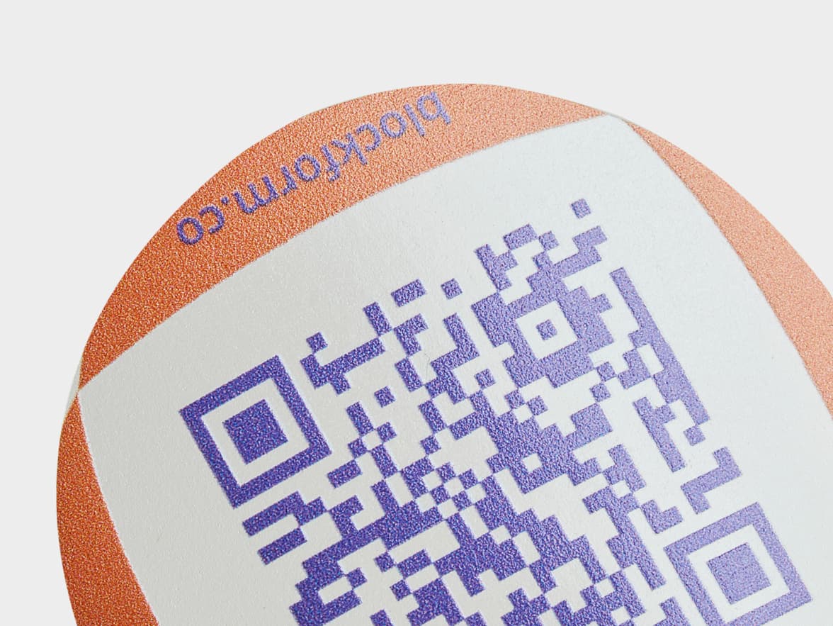 A close up of a customized clear round sticker with a purple QR code printed on it.