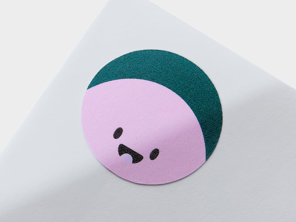 A close up of a round coated sticker with an animated face printed on it.
