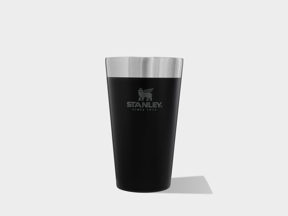 A black Stanley insulated tumbler with a stainless steel rim on a light background.