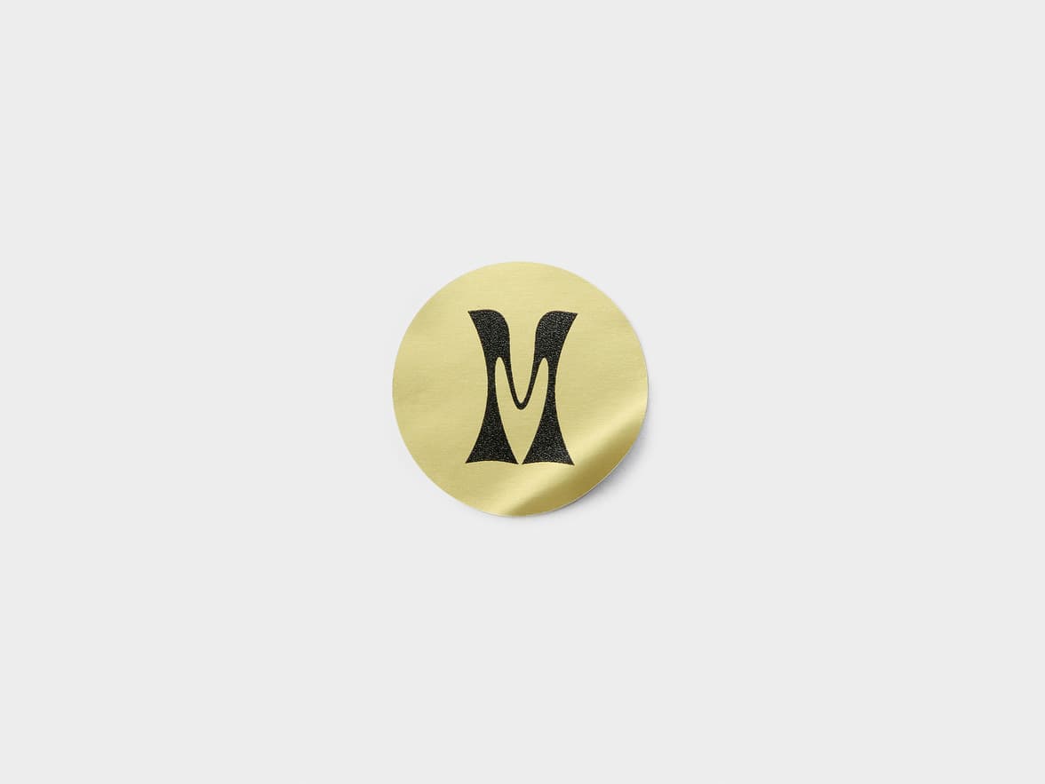 A round gold metallic sticker with black customization.