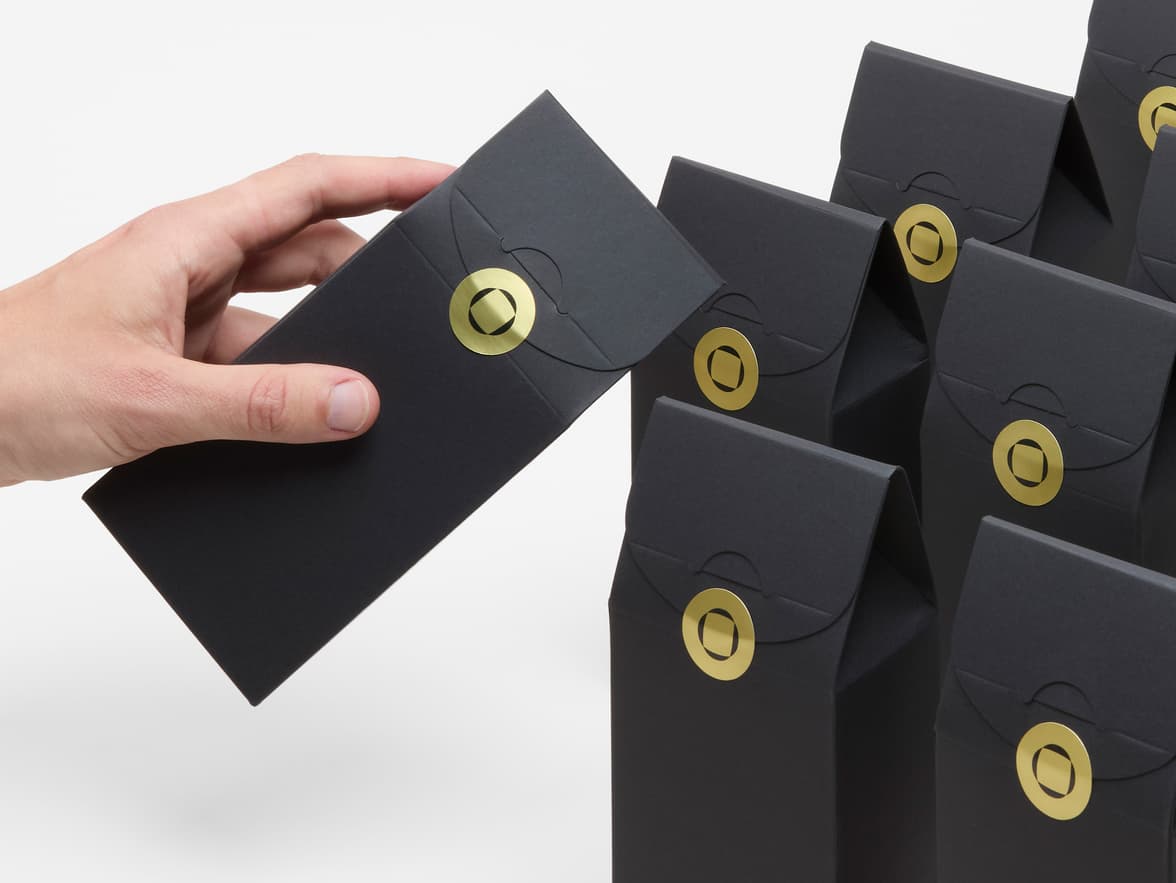 A collection of black packaging bags with a round gold metallic sticker placed on them.
