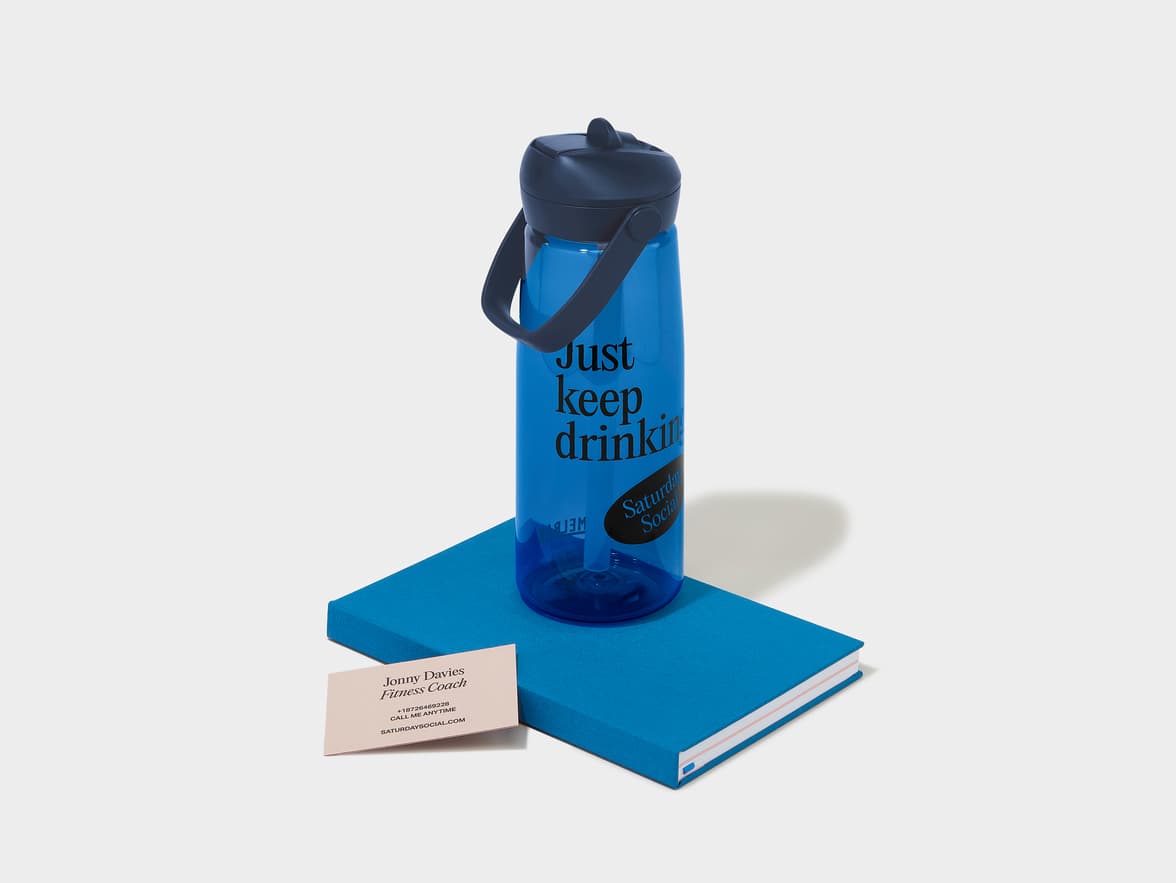 A blue water bottle with a black lid and handle, featuring the text 'Just keep drinking' and 'Saturday Social!'.