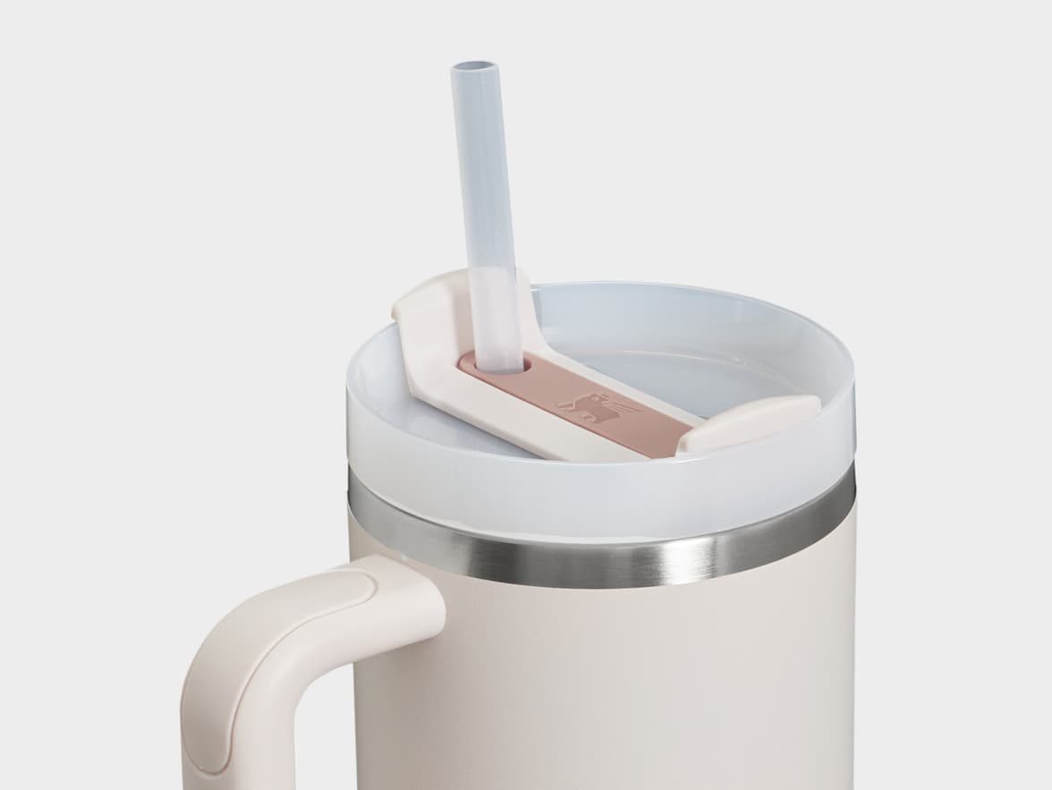 A light-colored travel mug with a handle, clear lid, and straw.
