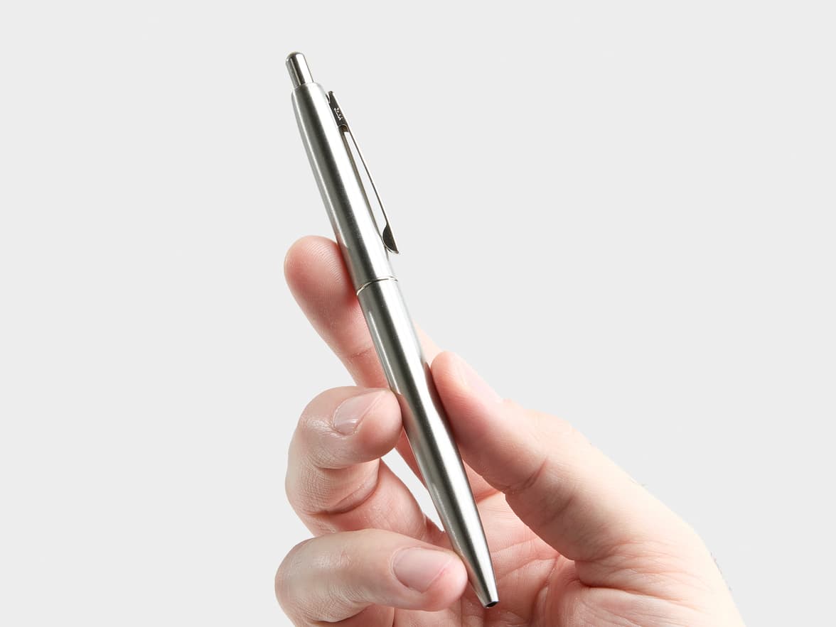 A hand holding a silver Zebra pen.